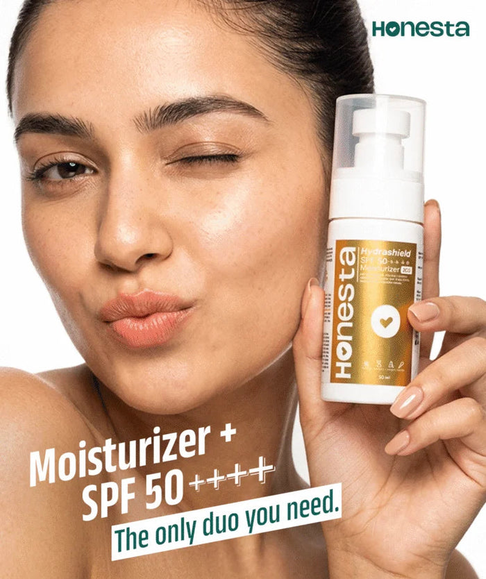 A woman holds a bottle of Honesta Hyaluhydrated Moisturizer + SPF 50++++ in one hand while applying or touching her face with the other. The image features a clean white background, promotional text, and the Honesta brand logo.
