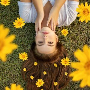 Upside down portrait of a woman lying on grass with yellow flowers in her hair.
